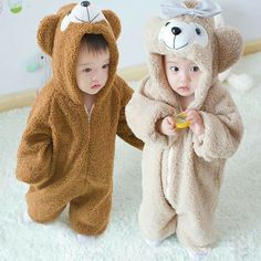 two toddlers dressed in animal onesuits standing next to each other