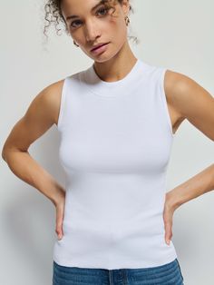 The sleeveless mock neck you covet, now in responsible Organic Rib. Chic, with an edge. Just like its namesake. (This one comes in White.) | Women's Joan Tank Top in White | Ethical Essentials White Fitted High Neck Tank Top, White High Neck Tank Top For Spring, White Fitted Turtleneck Tank Top, White Fitted Mock Neck Top With Funnel Neck, Stretch Sleeveless Mock Neck Top For Layering, Spring Sleeveless Mock Neck Top, White High Neck Stretch Tank Top, Sleeveless Mock Neck, Mock Neck