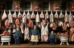 two men standing in front of fake meat hanging from hooks