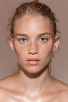 a woman with freckled hair and blue eyes is looking at the camera while wearing a bra