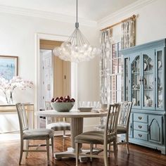 a dining room table with four chairs and a bowl of fruit on top of it