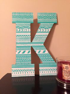 the letter k is made out of wood and sits on a table next to a candle