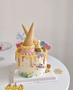 a birthday cake decorated with ice cream and toppings on a white table in front of a wall