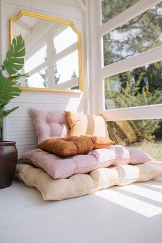 pillows are stacked on top of each other in front of a window with a mirror