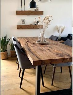 a wooden table with some chairs around it and shelves on the wall in the background