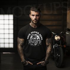 a man standing in front of a motorcycle with his hands on his hips wearing a black shirt