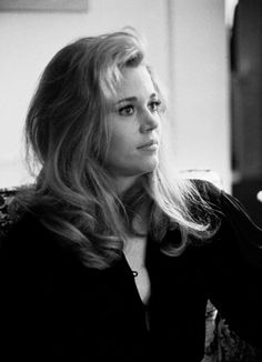 a black and white photo of a woman sitting on a couch with her hair blowing in the wind