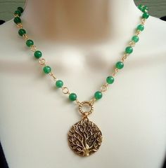 A beautiful sculpted gold tree of life pendant hangs from a hand made chain consist of green jade gemstones, all plated in 24 karat gold. This striking necklace is finished with a spring ring clasp. The necklace measures 16 inch in length, with 2 inches extension. Pendant measures 1.5 inch. Also available in sterling silver plate. Available in many color stones chain. Bohemian Gold Jewelry With Green Onyx, Bohemian Green Onyx Gold Jewelry, Gold Jade Necklace With Gemstone Beads, Gold Aventurine Beaded Necklaces, Handmade Gold Necklaces With Green Onyx, Handmade Gold Green Onyx Necklaces, Handmade Green Onyx Gold Necklace, Bohemian Gold Aventurine Necklace, Gold Emerald Necklaces With Gemstone Beads