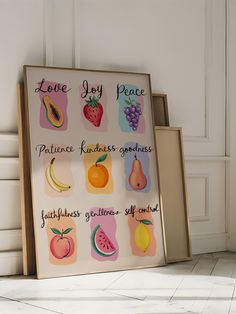 a sign with fruit and words on it in front of a white wall that says love joy peace