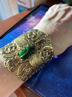 "Egyptian scarab green scarab cuff Wide cuff 2-1/2 inches, scroll pierced antique gold plating over brass.  Open in back for ease of wearing. Winged layered scarab wings with large resin and crystal detailed dark emerald green scarab. Adjustable size 7,8,9 Rich vintage patina Lucky beetle. Speaks life. This is a show stopper. Gorgeous! Limited edition. \"Angelina Verbuni Designs\" Made in USA MyElegantThings" Antique Gold Cuff Jewelry, Elegant Green Metal Cuff Bracelet, Handmade Green Cuff Bracelet For Formal Occasions, Arcane Jewelry, Scarab Wings, Egyptian Design Pattern, Emerald Green Jewelry, Dark Beauty Fashion, Egyptian Bracelet