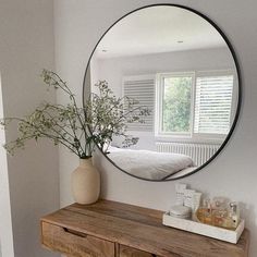 a round mirror on the wall above a dresser