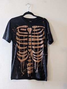 A classic bleached-out skeleton tee featuring the ribs on the front and the spine on the back. If you're a fan of this alternative goth style then this graphic tee is for you. READ THIS BEFORE ORDERING It takes 1 week to ship out due to my current workload. Message me if you need your shirt by a certain date before ordering. 100 % cotton Gildan brand, or ATC brand It can be made in size men's S-2X. Message me if you need a different size before ordering. A sizing chart is included in the images. Skeleton Shirt Design, Skeleton Bleach Shirt, Bleach Skeleton Shirt, Bleach Tshirt, Skeleton Clothes, Bleaching Clothes, Bleach Hoodie, Skeleton Tshirt, Goth Style