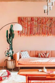 a living room filled with furniture and a large cactus hanging on the wall above it