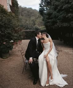 a bride and groom kissing in front of an outdoor dining table with chairs around them