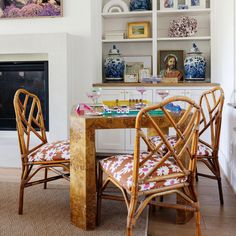 two chairs and a table in front of a fire place with pictures on the wall