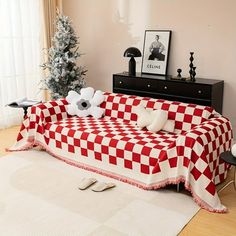 a red and white checkered couch sitting on top of a hard wood floor next to a christmas tree