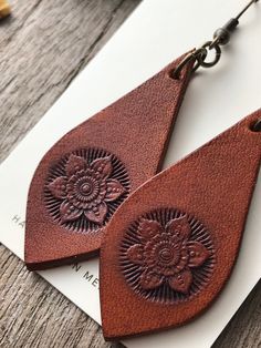 two brown leather earrings on top of a piece of paper