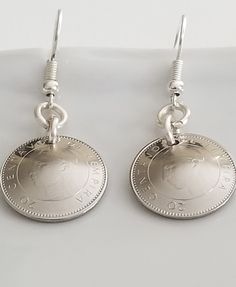 two pound coin earrings are hanging from hooks on a white surface, with the word love written below it