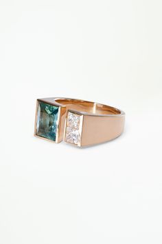 a gold ring with an aqua and white diamond set in the center, on a white background