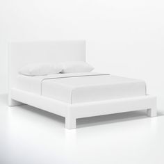 a bed with white sheets and pillows on it