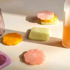 four different colored cookies next to a bottle of liquid on a table with other items