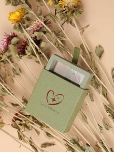 a green box sitting on top of some dried flowers