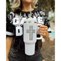 a woman holding a cup with a straw in her hand and a cross on it