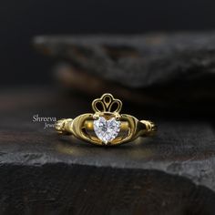 a heart shaped diamond ring sitting on top of a rock