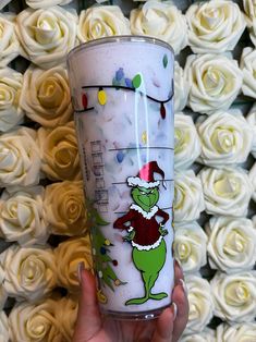 a hand holding a starbucks cup with the grin on it and white roses in the background