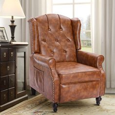 a brown leather chair sitting on top of a rug next to a lamp and dresser