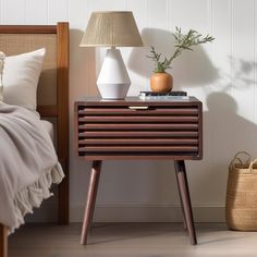 a nightstand with two vases on it next to a lamp and bed in a room