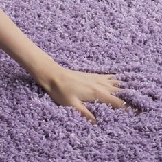 a person's hand on top of a purple area rug that is very soft