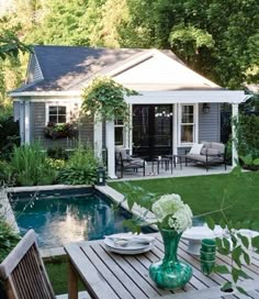 a backyard with a table and chairs next to a pool in the middle of it