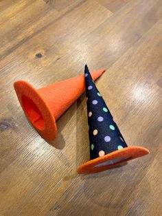 an orange and black cone with polka dots on it sitting on top of a wooden floor