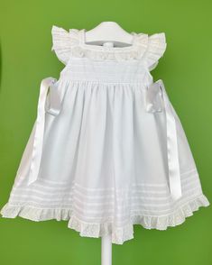 A simple and modern white dress for baby girls to wear on a special day. It has buttons on the back for closure and comes with a matching bonnet. Made in Spain Inside: 65% polyester 35% cotton Dry Clean Final sale, no exchanges nor returns are accepted White Sleeveless First Communion Dress With Ruffles, Classic Ruffled Dresses For Dress-up, Classic Ruffled Dresses For Dress-up Occasions, Cotton Ruffle Dress For First Communion, First Communion Cotton Dress With Ruffles, Classic Ruffle Dress For First Communion, Classic Cotton Dress For Dress-up Occasions, Classic Cotton Dresses For Dress-up, Classic First Communion Dress With Ruffles