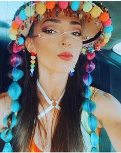 a woman in a car wearing a hat with beads on it's head and multicolored hair