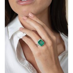 a woman wearing an emerald and diamond ring