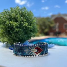 a beaded bracelet sitting on top of a table next to a pool