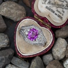 This gorgeous ring is centered with one (1) cushion cut natural pink sapphire set into a four-prong head. The top half of the ring is accented with ninety- six (96), bead/prong set, round brilliant cut diamonds. The diamonds are bordered with milgrain edging. The ring measures 12.8mm at the top, rises 7.1mm above the finger, tapering to 4.0mm wide and 1.5mm thick at the base of the shank. This ring is currently a size 5.75. Formal Pink Sapphire Rings With Cushion Cut, Formal Pink Sapphire Cushion Cut Rings, Pink Platinum Ruby Ring For Wedding, Pink Sapphire Ring In Platinum For Wedding, Pink Sapphire Platinum Ring For Wedding, Pink Cushion Cut Diamond Ring Fine Jewelry, Pink Cushion Cut Brilliant Ring, Fine Jewelry Pink Sapphire Cushion Cut Ring, Fine Jewelry Pink Sapphire Ring With Diamond Accents