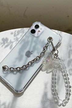 an iphone with a chain attached to it sitting on top of a table next to a cell phone