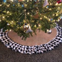 a christmas tree skirt is on the floor in front of a christmas tree with lights