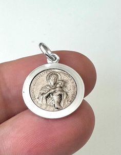 This spiritually significant silver-colored protection pendant celebrates the Thrice Admirable Mother of Schoenstatt, a deep-rooted devotion to Saint Mary and Child Jesus. Measuring 2.4 cm tall and 1.5 cm wide, this pendant is finely crafted, with the front featuring a detailed image of Saint Mary and Child Jesus surrounded by the words "Thrice Admirable Mother of Schoenstatt." The back features another encouraging inscription: "God bless you," making this pendant a powerful symbol of faith and Miraculous Medal Pendant Gift, Engraved Coin-shaped Spiritual Jewelry And Charms, Engraved White Gold Spiritual Jewelry And Charms, Silver Miraculous Medal Round Pendant, Silver Miraculous Medal Jewelry As Gift, Sterling Silver Spiritual Jewelry For Memorial, Silver Spiritual Locket Jewelry, Spiritual Round Pendant Locket, Silver Locket Jewelry For Blessing