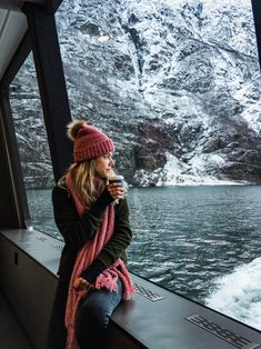 a woman sitting on top of a window sill next to a body of water