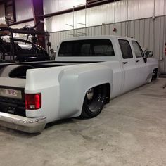 a white truck parked in a garage next to another car and motorcycle on the other side