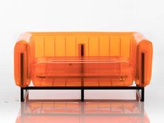 an orange plastic couch sitting on top of a white floor next to a black metal frame