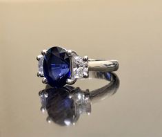 Dekara Designs Collection Metal- 90% Platinum, 10% Iridium. Stones- 1 Natural Untreated 3.88 Carat Oval Cut Ceylon Blue Sapphire. 2 Moon Cut Diamonds, F-G Color VS1 Clarity 0.77 total carats This ring is a size 6, but could be sized up or down a few sizes. This ring could be made in your specific size within 5-10 business days. Could take a little more time due to the ceylon sapphire being a rare stone. The sapphire may be a bit smaller or bigger. We can make the same design in a smaller or bigg Formal Blue Sapphire Ring Gia Certified, Blue Oval Sapphire Ring With Vvs Clarity, Oval Blue Sapphire Ring With Vvs Clarity, Blue Gia Certified Diamond Ring For Formal Occasions, Blue Sapphire Ring With Brilliant Oval Cut, Gia Certified Blue Oval Rings, Blue Sapphire Ring With Brilliant Cut For Wedding, Blue Oval Diamond Ring With Prong Setting, Oval Blue Sapphire Ring With Diamond Cut