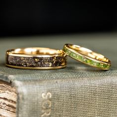 two gold wedding rings sitting on top of an old book with moss growing in them