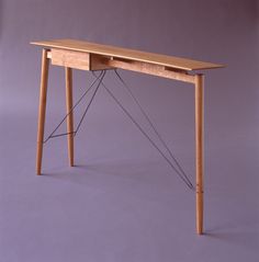 a wooden desk with two legs and a string attached to the top, on a purple background