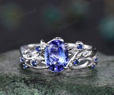 an oval tanzante and blue sapphire ring with leaves on the band, set in white gold