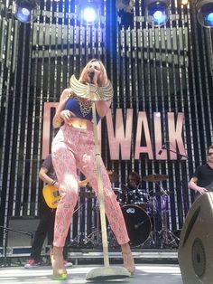 a woman standing on top of a stage holding a guitar